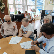 Другая группа читателей и волонтёров. Двое из них разместились за рабочим местом незрячего специалиста, остальные - за общим столом.
